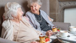 Two ladies enjoying cake and tea in a care home
