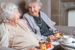 Two ladies enjoying cake and tea in a care home